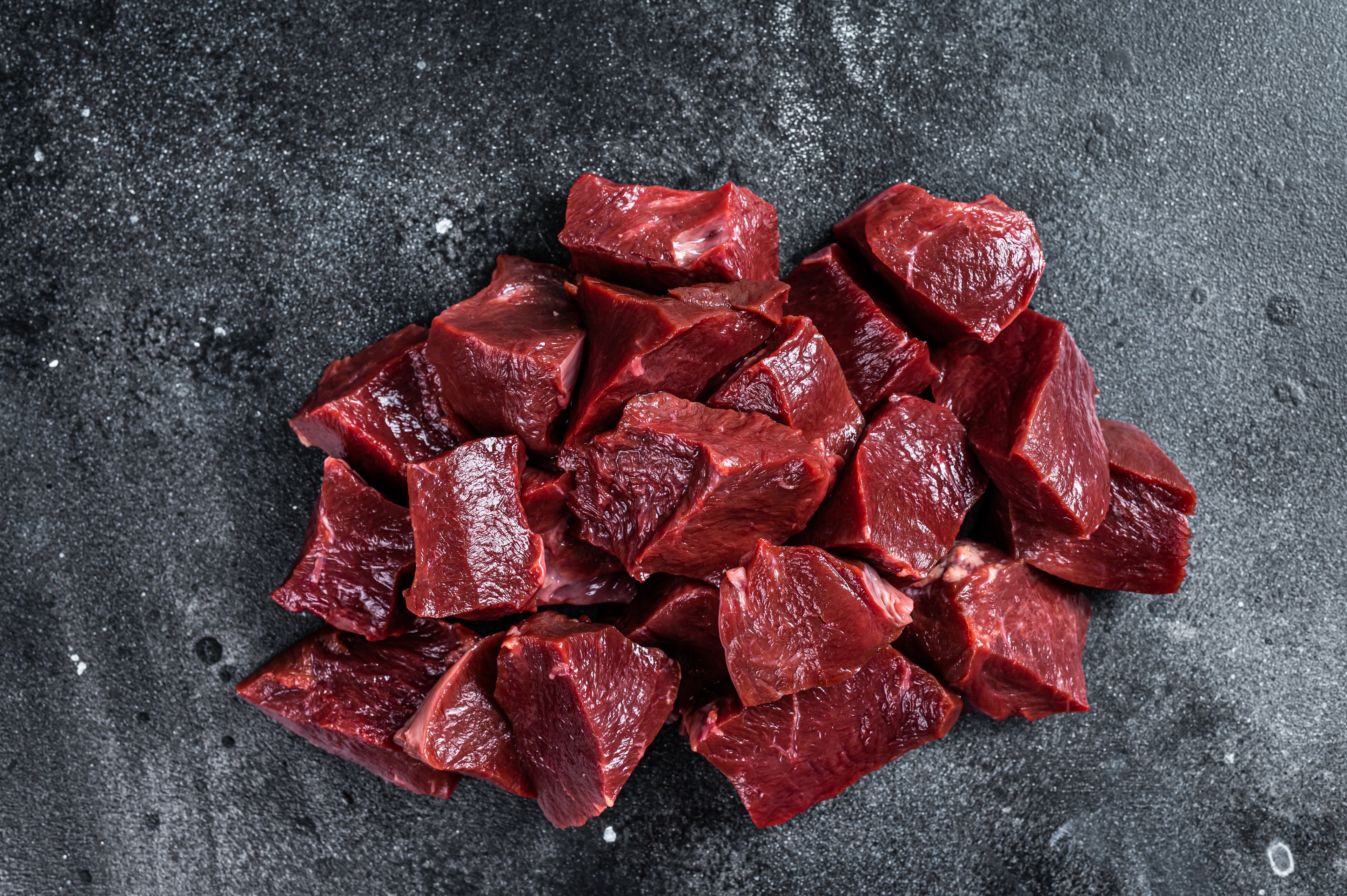 Raw beef liver cut into chunks on a dark textured surface — a nutrient-rich ingredient used in PupSip hydration mix for dogs