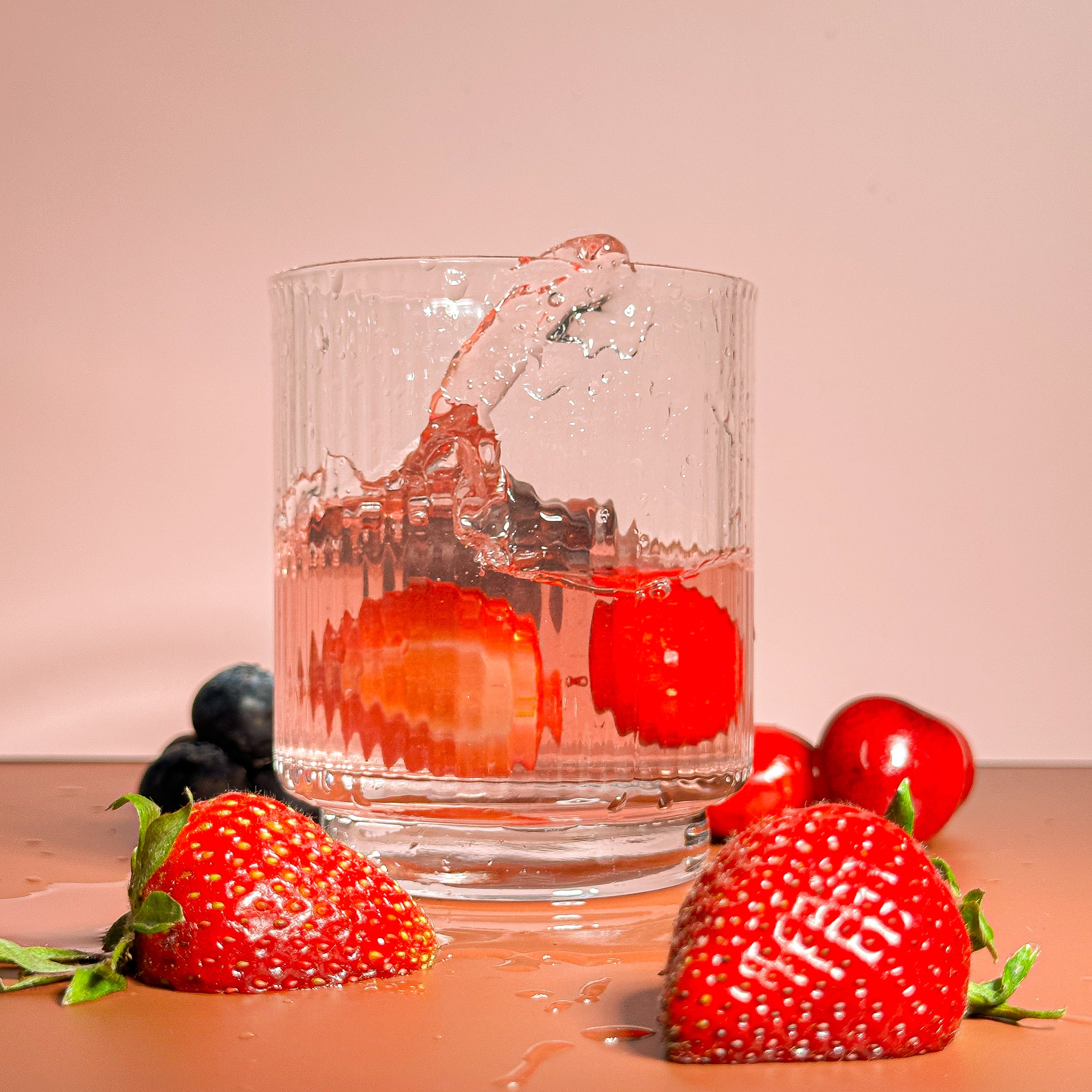 Glass of berry-infused water splashing over fresh strawberries, cherries, and blueberries—evokes PupSip Berry Boost’s fruity, refreshing hydration